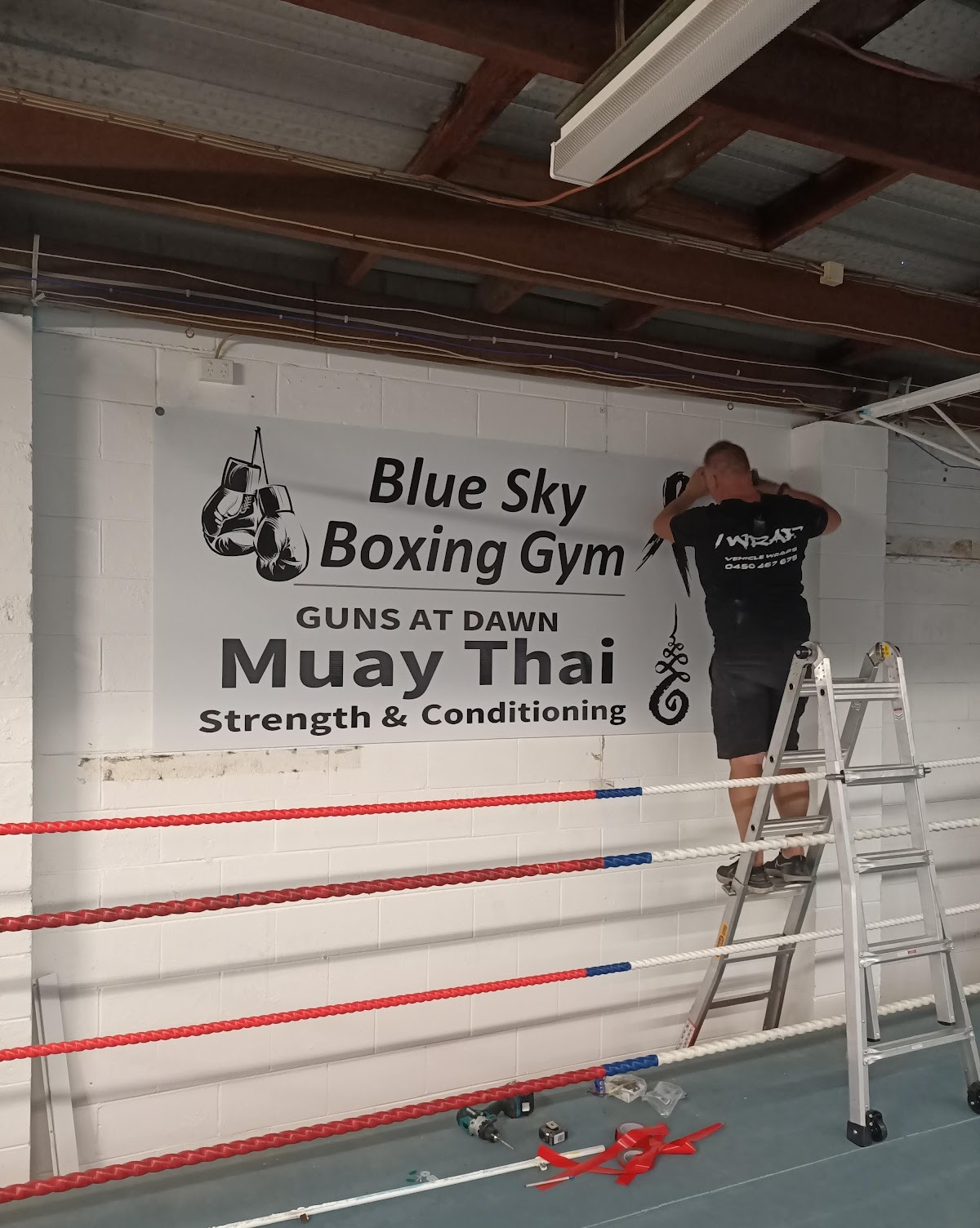The Guns At Dawn Muay Thai banner being put up on the gym wall